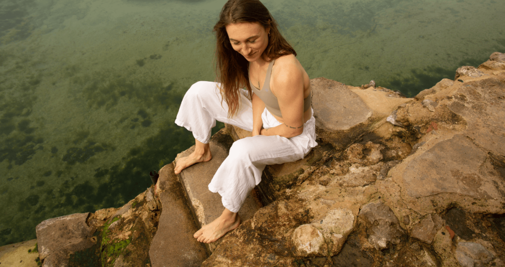 Woman sitting by a natural pool.