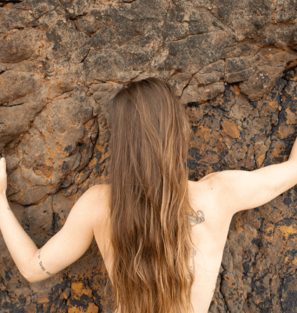 Woman in front of a rock.