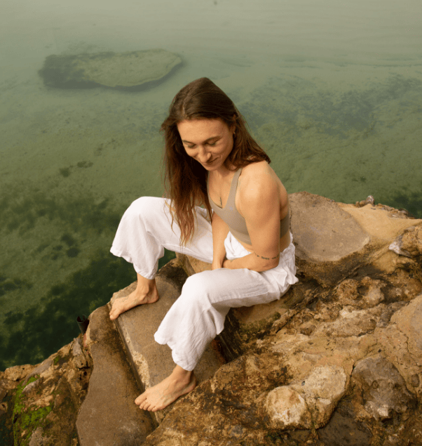 Woman sitting by a natural pool.